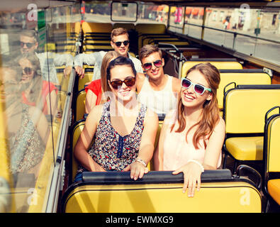 group of smiling friends traveling by tour bus Stock Photo