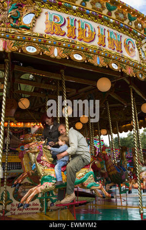 UK, England, Cheshire, Chelford, Astle Park Traction Engine Rally, grandfather and grandson on traditional carousel Stock Photo