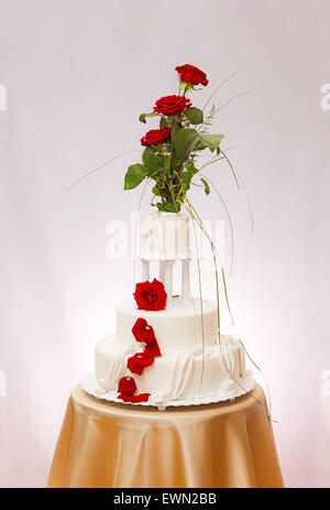 Three-storied white wedding cake with real rose decoration Stock Photo
