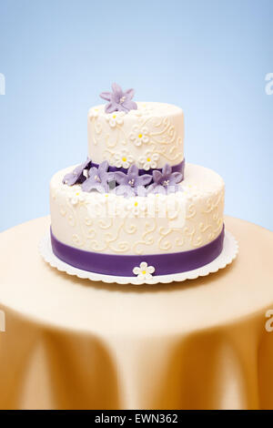Two-storied white wedding cake with violet marzipan flowers decoration Stock Photo