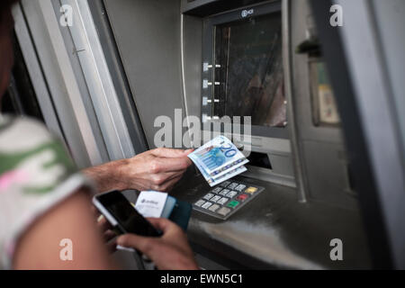 People withdraw money from an automated teller machine (ATM) in Athens, Greece on the 29th of June 2015. Photo: Socrates Baltagiannis/dpa Stock Photo