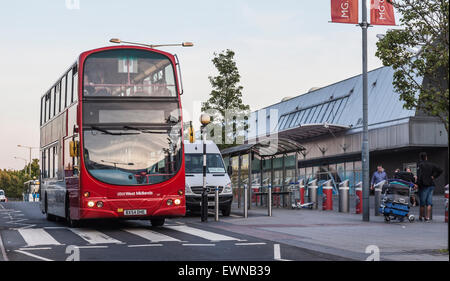 Red double decker National Express West Midlands bus and  airport minibus at a bus stop outside Arrivals, Birmingham Airport UK Stock Photo