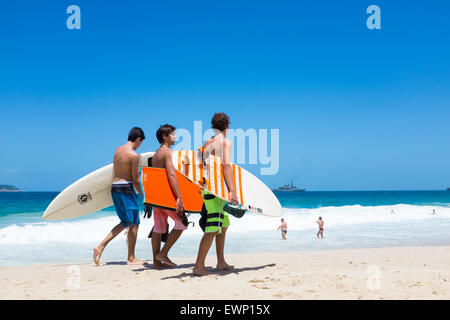 RIO DE JANEIRO, BRAZIL - MARCH 24 2015: Group of young Brazilian surfers walk on the shore of Ipanema Beach with surfboards. Stock Photo