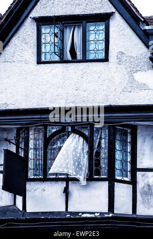 old house in Tudor style with a curtain blowing out of a window Stock Photo