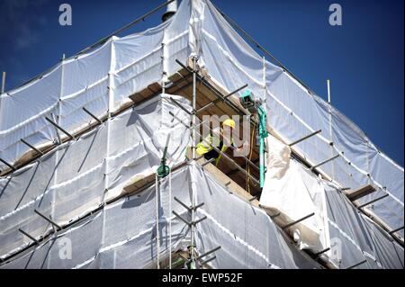 A construction worker leans out of scaffolding on a new build housing site. Stock Photo