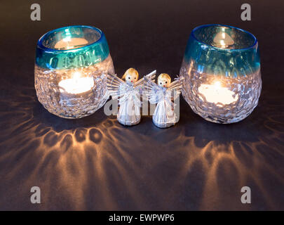 Two little angels and reflections of tea lights isolated on black background Stock Photo