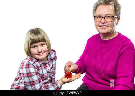 Caucasian grandmother putting euro coin in granddaughter's  piggy bank for saving isolated on white background Stock Photo