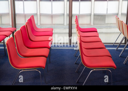 Red chairs lined up in an office space in the UK Stock Photo
