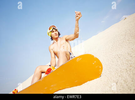 Handsome guy with sandboard sitting on beach Stock Photo