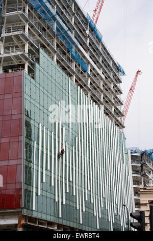 Worker on rope, cladding new building at Victoria, London. England ...