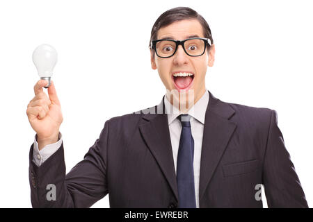 Young excited businessman in a black suit holding a light bulb and looking at the camera isolated on white background Stock Photo