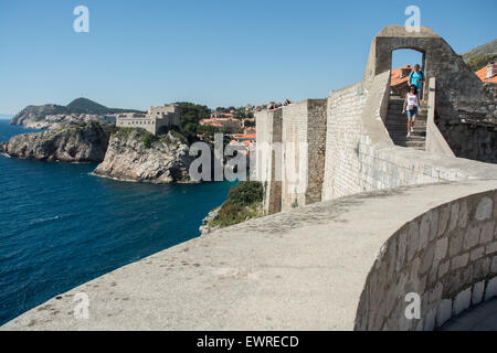 tourists on old city wall with fort lovrijenac or st. lawrence fortress, often called 'dubrovnik's gibraltar', in background, dubrovnik, croatia Stock Photo