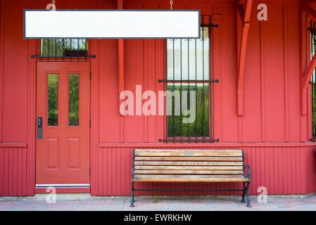 Empty bench by blank sign against red wooden walls Stock Photo