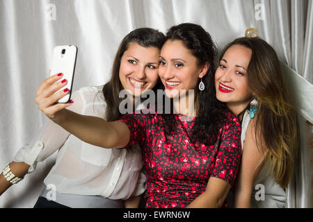 Group of young cheerful smiling women make selfie. Three beauty girls have fun in the restaurant Stock Photo