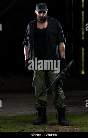 Action Hero Muscled Man Holding Machine Gun - Standing In Abandoned Building Wearing Green Pants Stock Photo