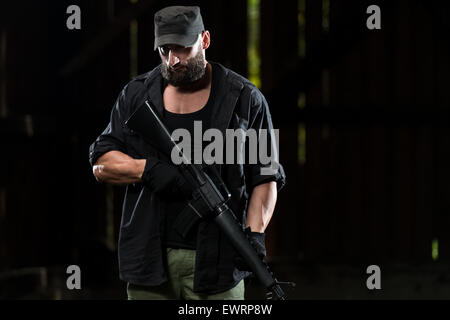 Action Hero Muscled Man Holding Machine Gun - Standing In Abandoned Building Wearing Green Pants Stock Photo