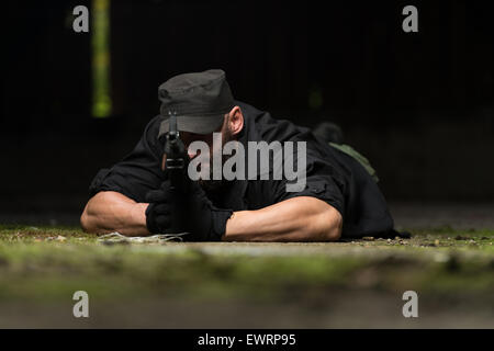 Action Hero Muscled Man Holding Machine Gun - Lying In Abandoned Building Wearing Green Pants Stock Photo