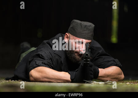 Action Hero Muscled Man Holding Machine Gun - Lying In Abandoned Building Wearing Green Pants Stock Photo