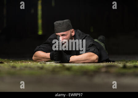 Action Hero Muscled Man Holding Machine Gun - Lying In Abandoned Building Wearing Green Pants Stock Photo