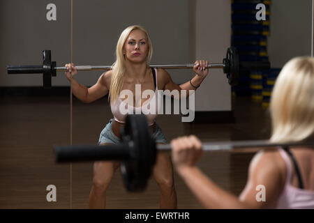 Young Woman Performing Barbell Squats - One Of The Best Body Building Exercise For Legs Stock Photo