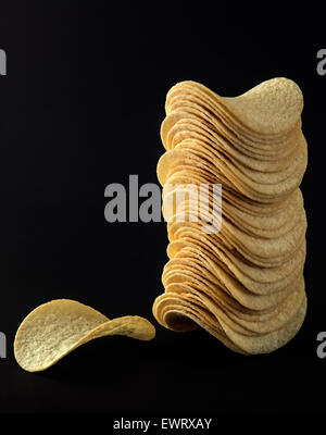 Pringles crisps pile or Crispy potato chips on black background as unhealthy food concept Stock Photo
