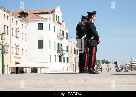 Two Carabinieri stand watching events and keeping law on steps near Venice waterfront. Stock Photo