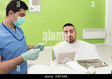 Happy Smiling Patient Says Personal Information While The Dentist Writes On The Card Stock Photo