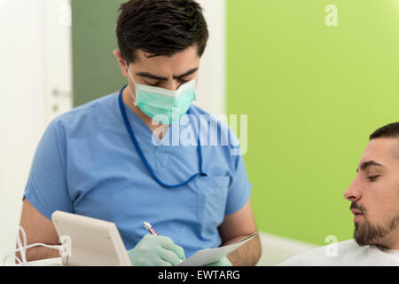 Happy Smiling Patient Says Personal Information While The Dentist Writes On The Card Stock Photo