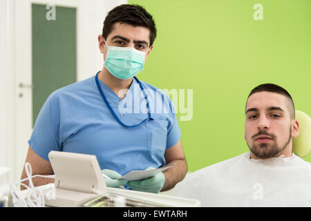 Happy Smiling Patient Says Personal Information While The Dentist Writes On The Card Stock Photo