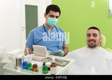 Happy Smiling Patient Says Personal Information While The Dentist Writes On The Card Stock Photo