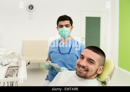 Happy Smiling Patient Says Personal Information While The Dentist Writes On The Card Stock Photo