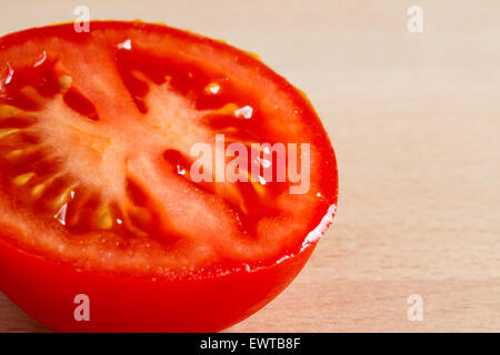 Half of a red ripe tomato on a wooden board Stock Photo