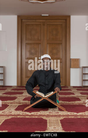 Black African Muslim Man Reading Holy Islamic Book Koran Stock Photo