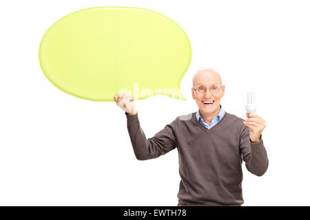 Studio shot of a joyful mature man holding an energy efficient light bulb and a big yellow speech bubble Stock Photo