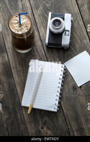 Analogue photo camera on a table with coffee and paper notes Stock Photo