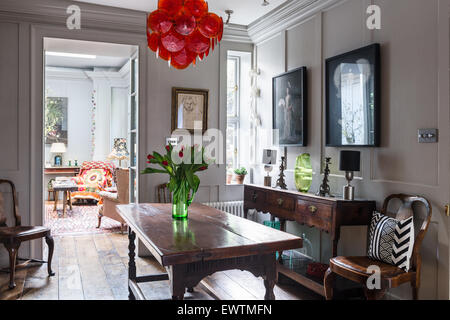 Pair of photographs by Chan-Hyo Bae above oak dresser in panelled dining room with 1960's red glass disc chandelier by Vistosi Stock Photo