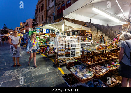 Shops line, souvenirs stand with traditional goods, Old Venetian harbour waterfront Crete Chania Greece evening atmosphere Stock Photo