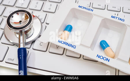 Blue Stethoscope and pill box with labeling time of day on computer keyboard Stock Photo