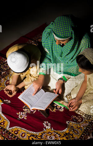 indian Muslim mother and kids reading Quran book Stock Photo