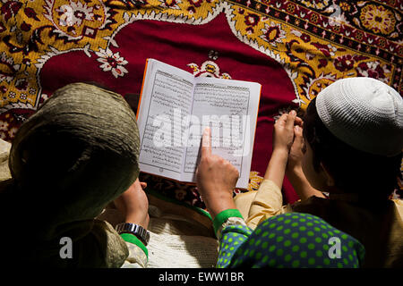 indian Muslim mother and kids reading Quran book Stock Photo