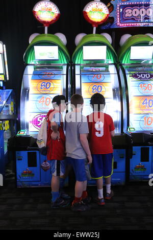 Three kids playing an arcade game together Stock Photo - Alamy