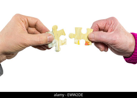 Two hands of man and woman joining uniting fitting puzzle pieces isolated on white background Stock Photo