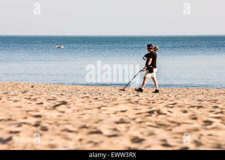 On a sunny Spring day, a, detectorist, using metal detector after most tourists/holiday makers have left beach looking for lost items/treasure Stock Photo