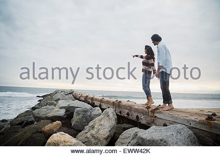 Barefoot couple pointing on ocean jetty