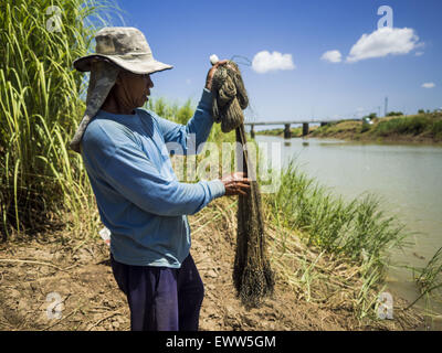 July 1, 2015 - Pa Tan, Lopburi, Thailand - A rice farmer does some subsistence fishing in an irrigation canal in Lopburi province. Normally the canal is too full of fast flowing water for the farmers to fish in it. One farmer said nobody in their community could remember the canal ever being this low. Central Thailand is contending with drought. By one estimate, about 80 percent of Thailand's agricultural land is in drought like conditions and farmers have been told to stop planting new acreage of rice, the area's principal cash crop. Water in reservoirs are below 10 percent of their capacity, Stock Photo