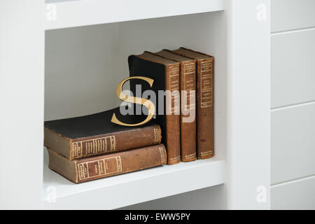 Gold Letter S leaning on antique law books within modern shelving Stock Photo