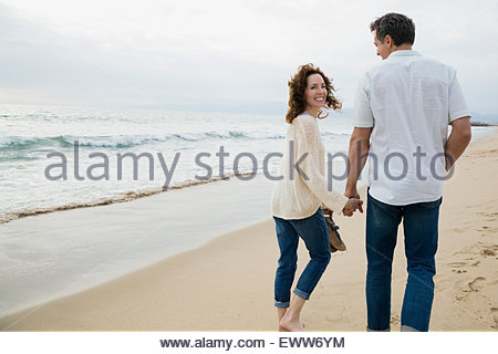 Portrait couple holding hands walking on beach