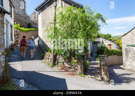 Two young people walking through the narrow lanes of a Peak District village in Summer. Castleton, Derbyshire, England, UK Stock Photo