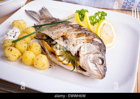 Grilled carp fish with rosemary potatoes and lemon, close up Stock Photo