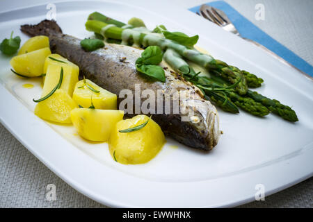 Grilled trout with green asparagus and rosemary potatoes, sauce Stock Photo